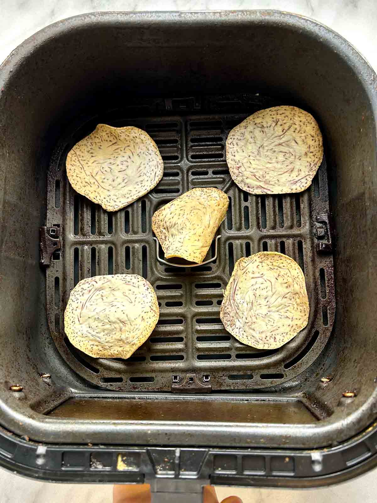 cooked taro chips in air-fryer basket.