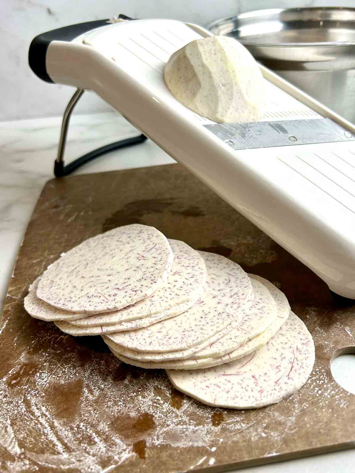 taro being sliced on mandolin.