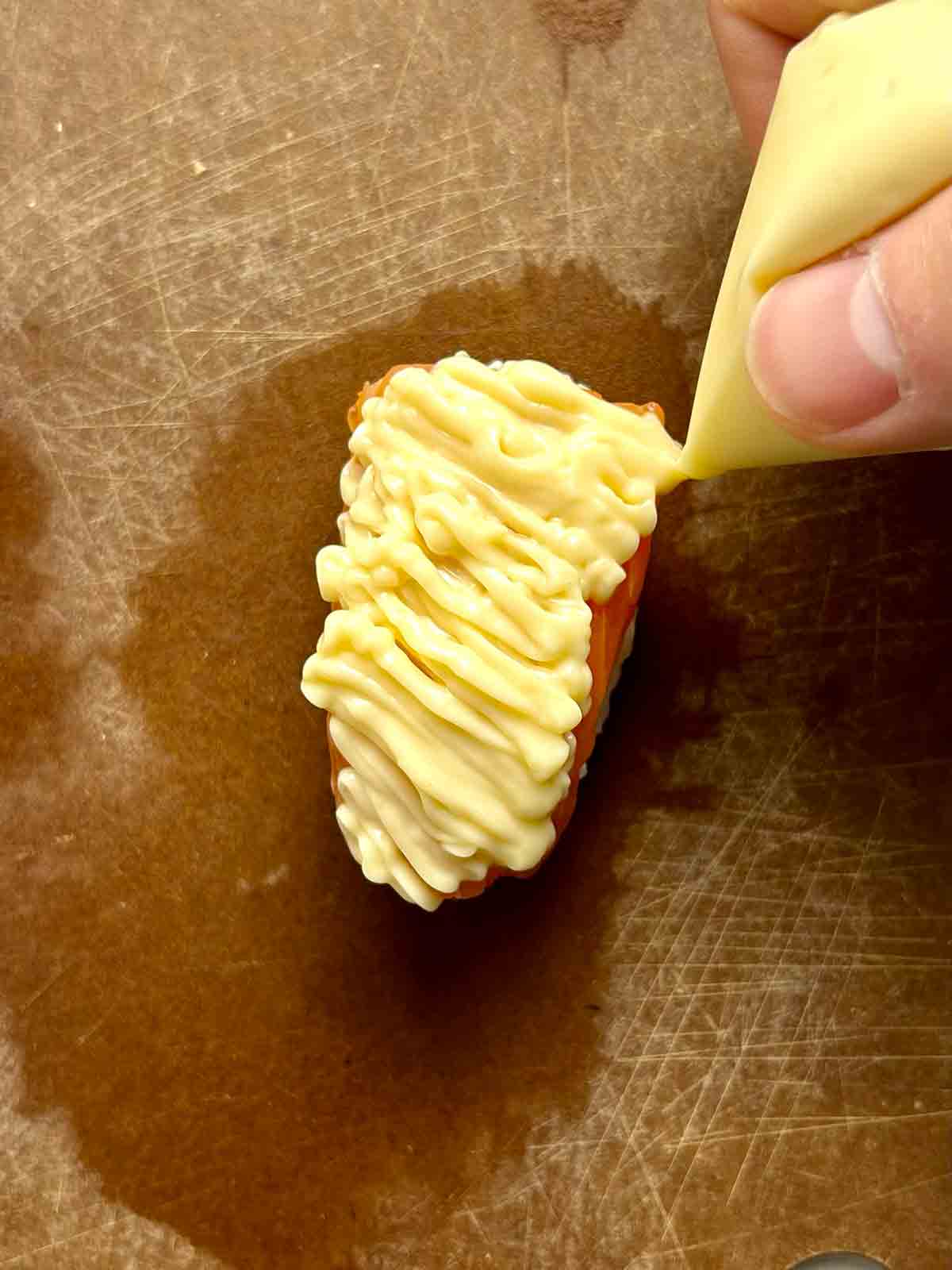 mayonnaise sauce being piped onto salmon.