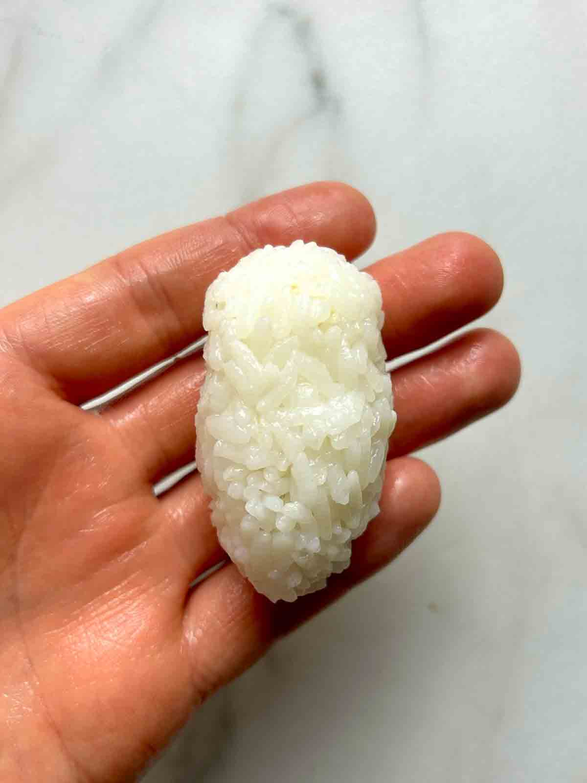 ball of rice squeezed into a football shape in hand.