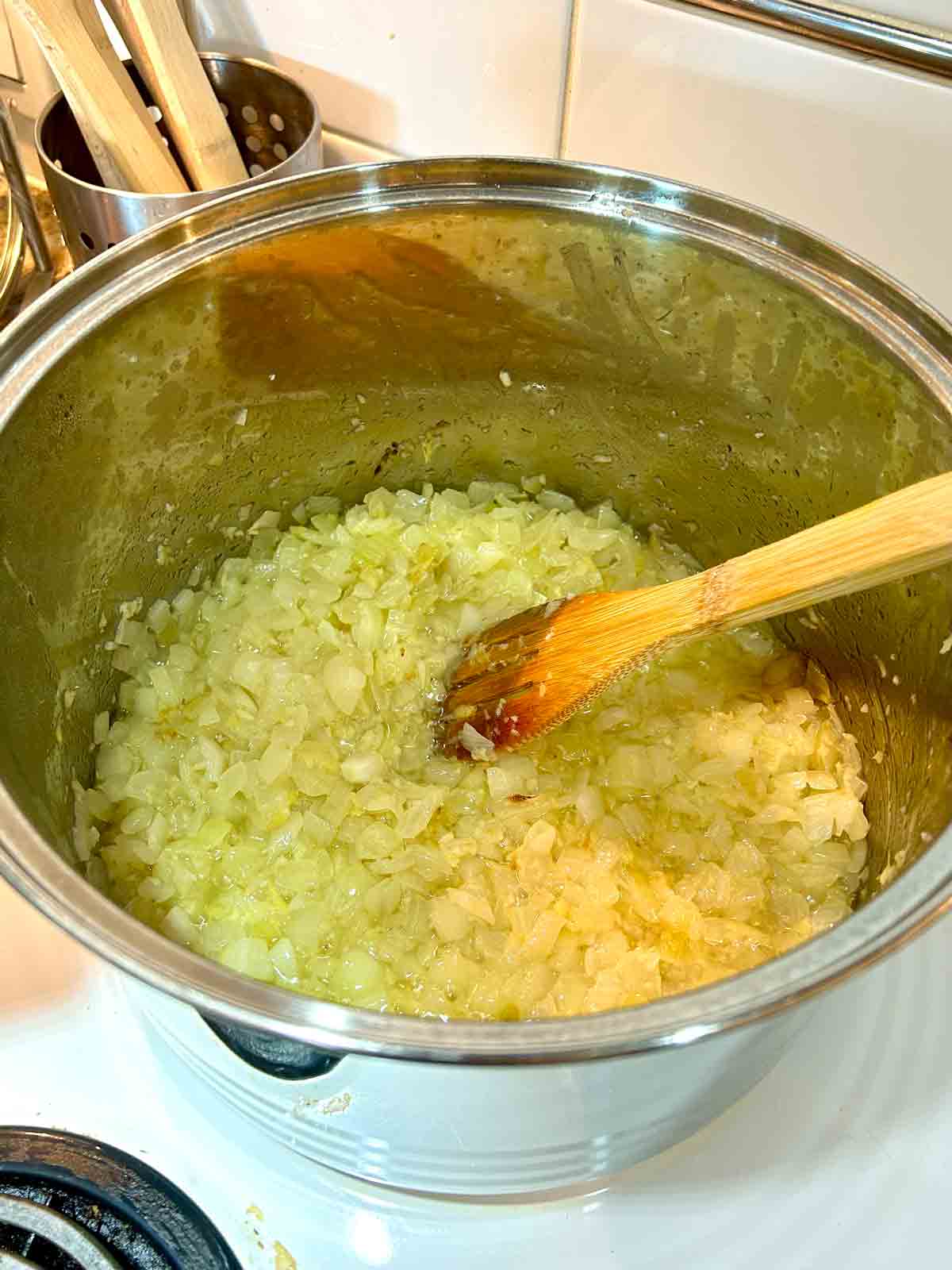 chopped onions being cooked until golden in large pot.