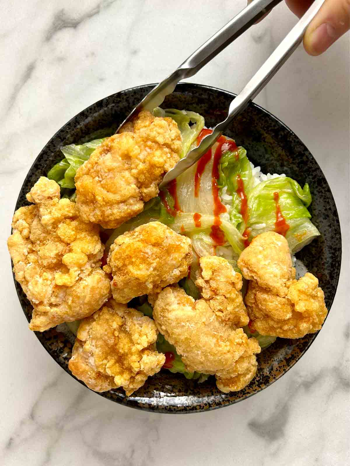 piece of chicken being added to chicken karaage don.