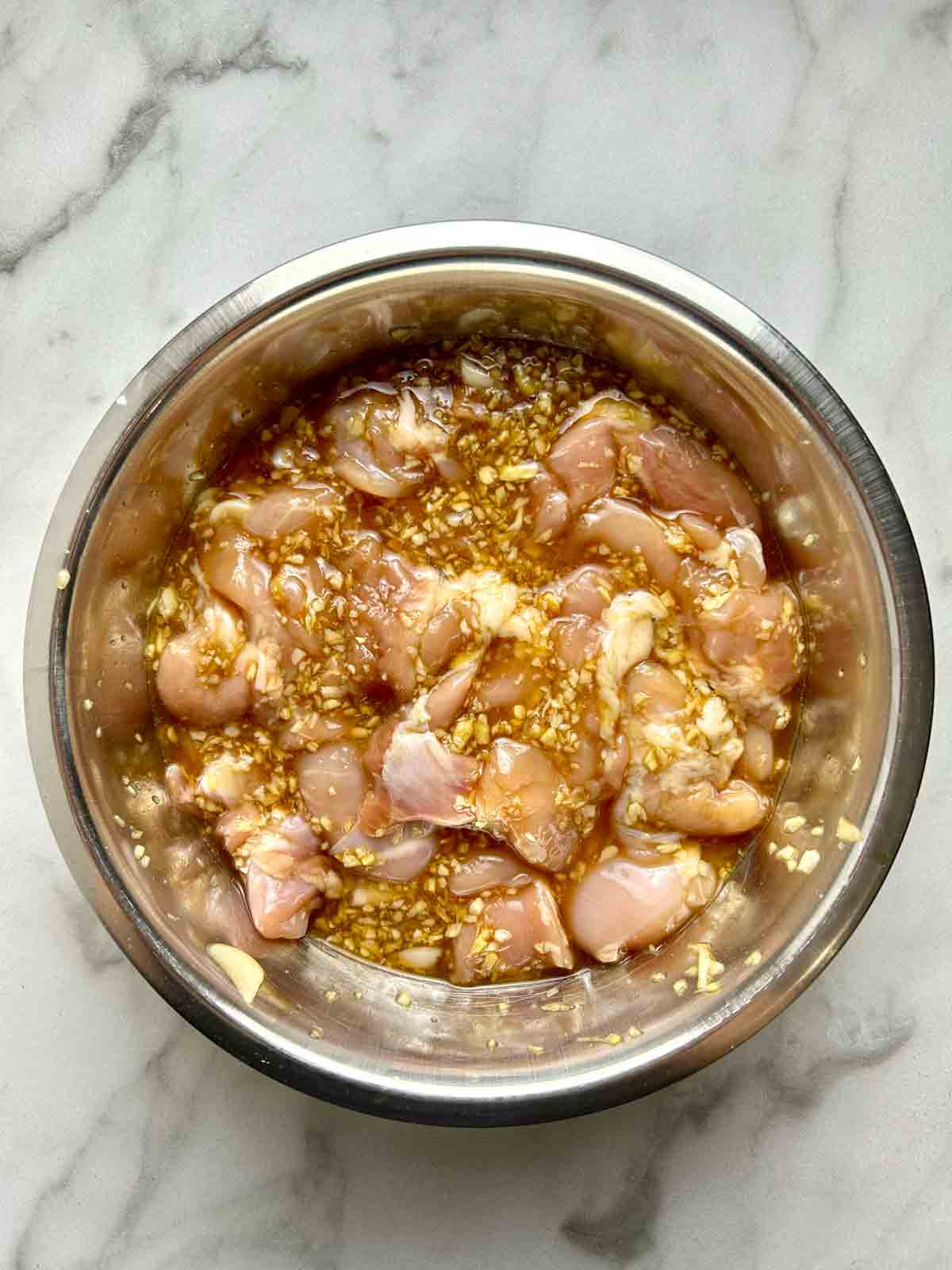 pieces of chicken being marinated in bowl.