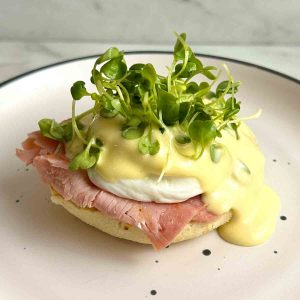 eggs benedict with hollandaise and microgreens on top.