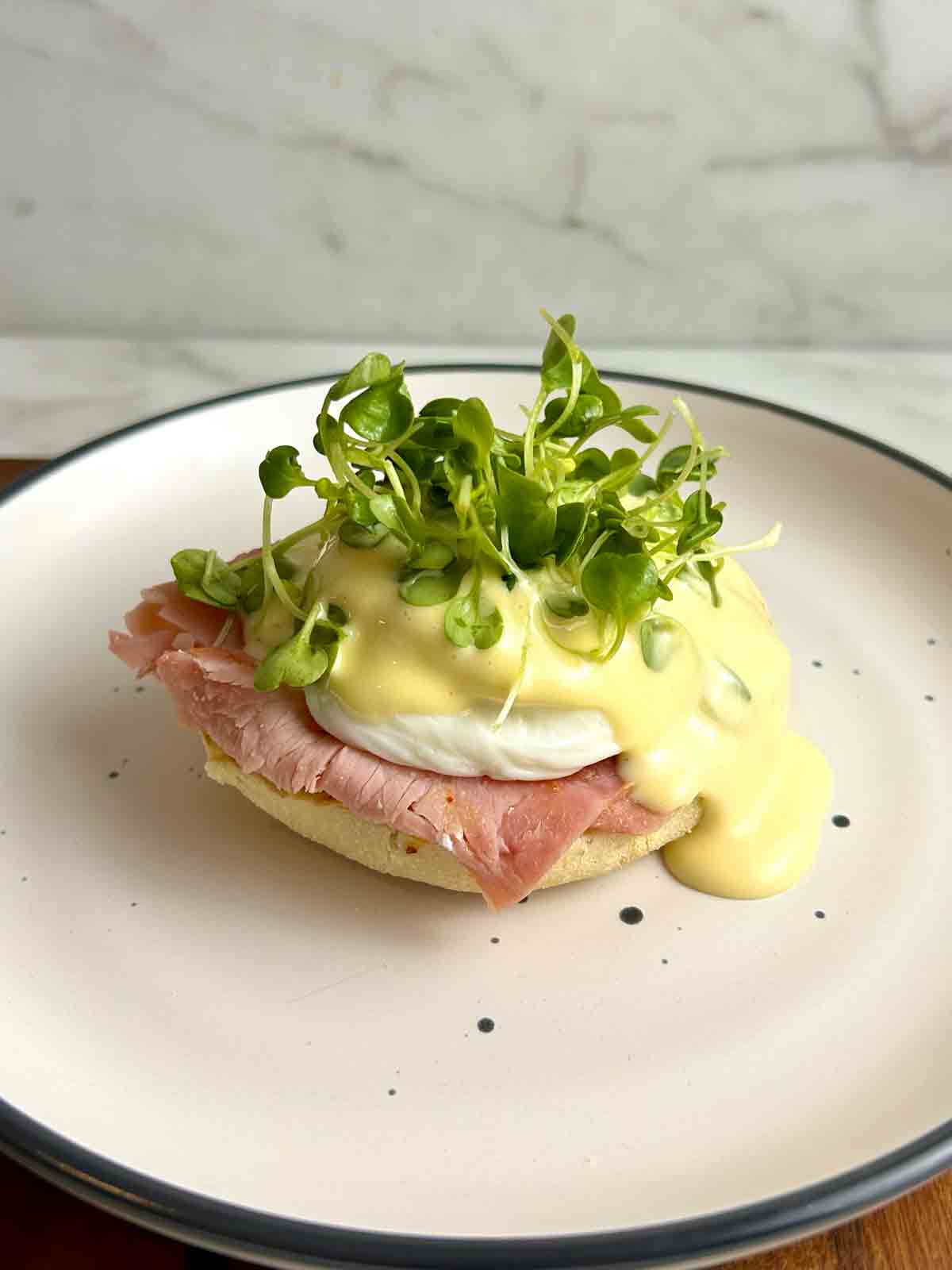 eggs benedict with hollandaise and microgreens on top.