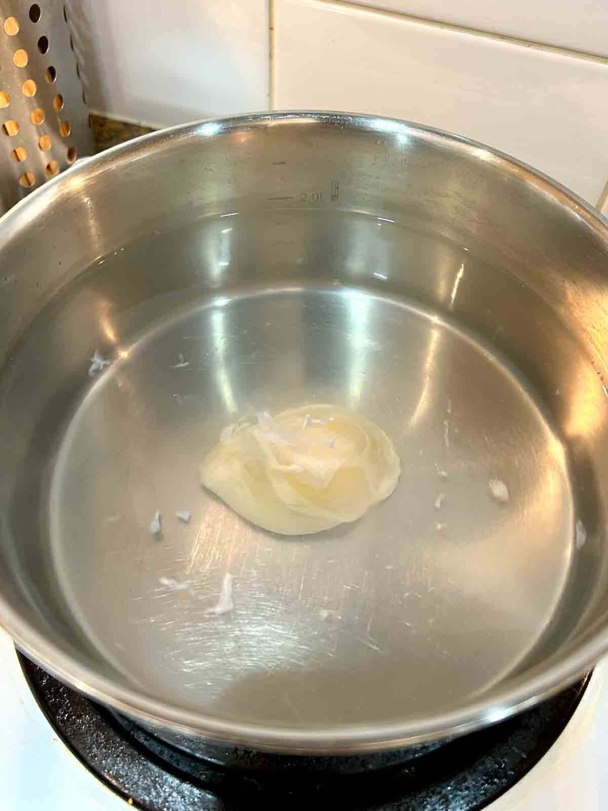 egg being poached in pot of water.