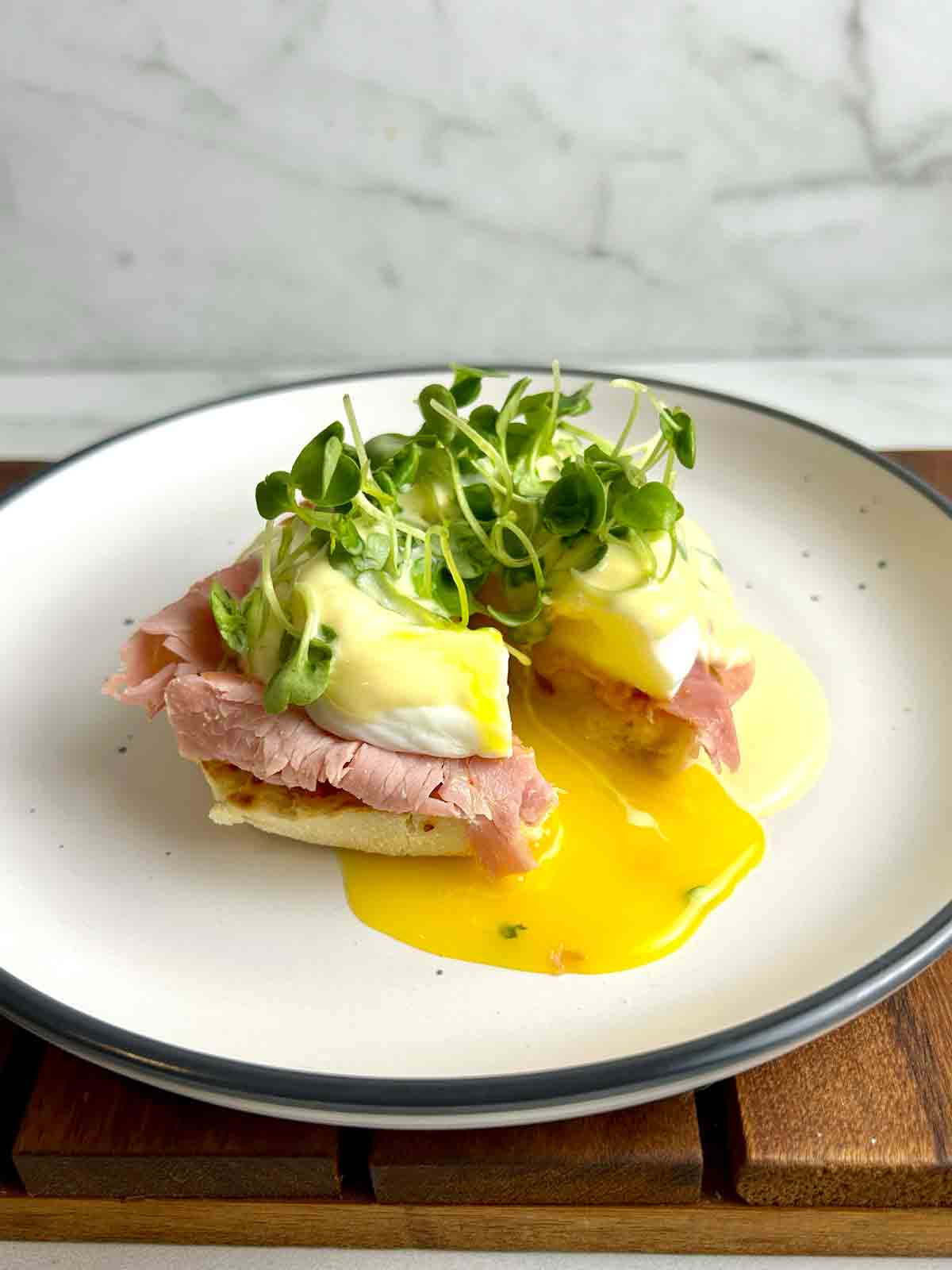 eggs benedict split open to show oozing yolks from poached egg.