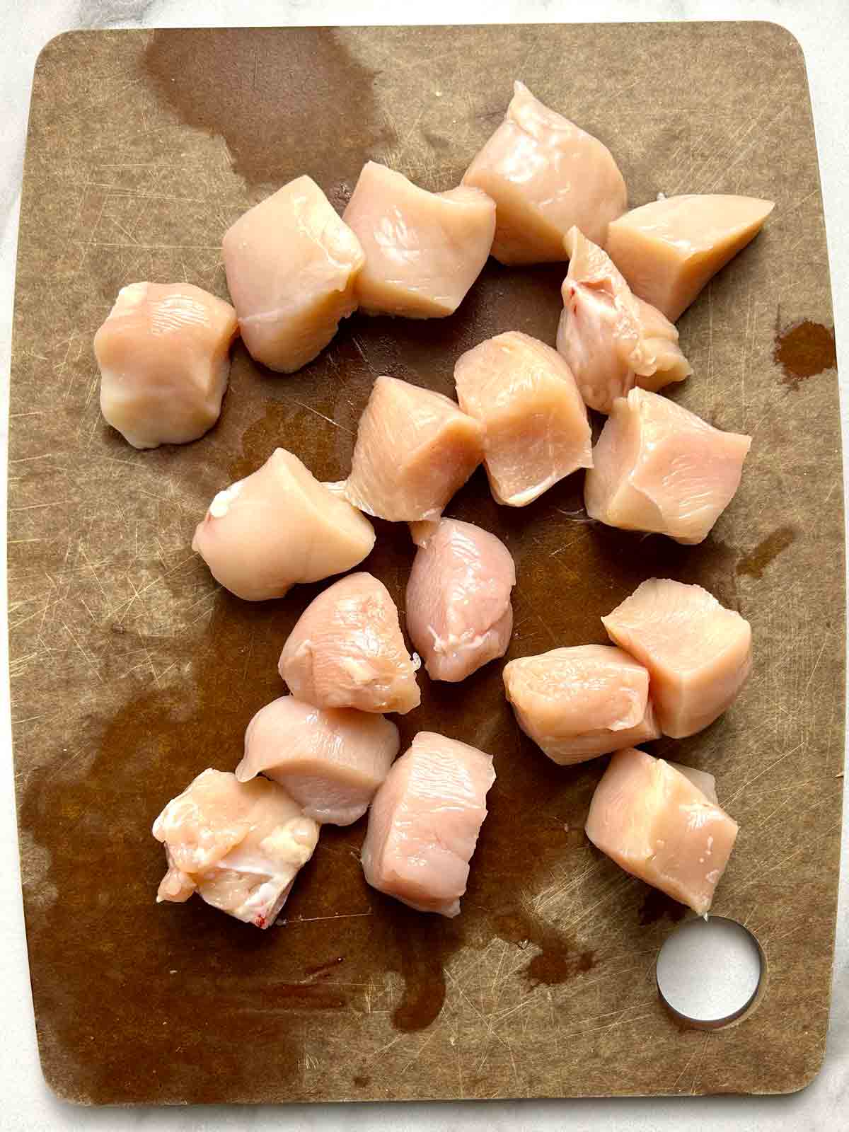 chicken breast cut into cubes on cutting board.