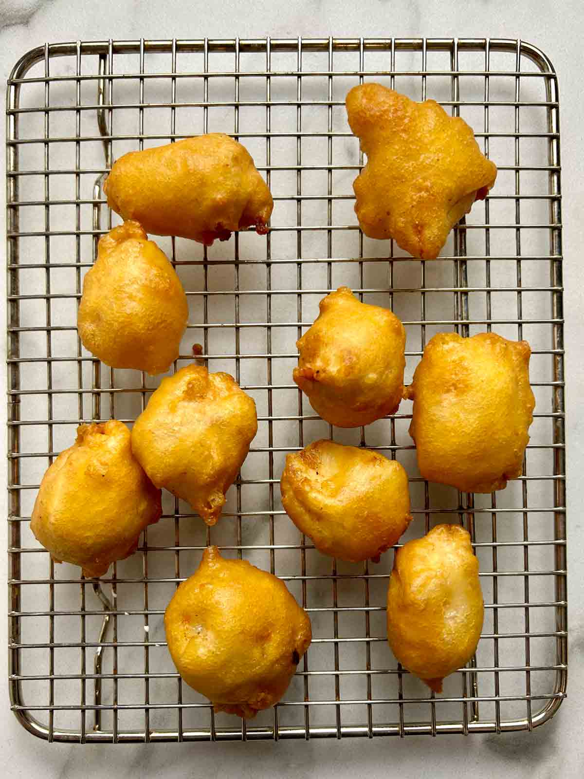 fried chicken balls draining excess oil on wire rack.