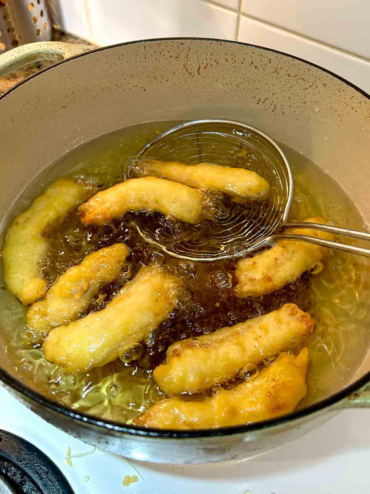 golden brown chicken fingers after 6 minutes of frying in oil.