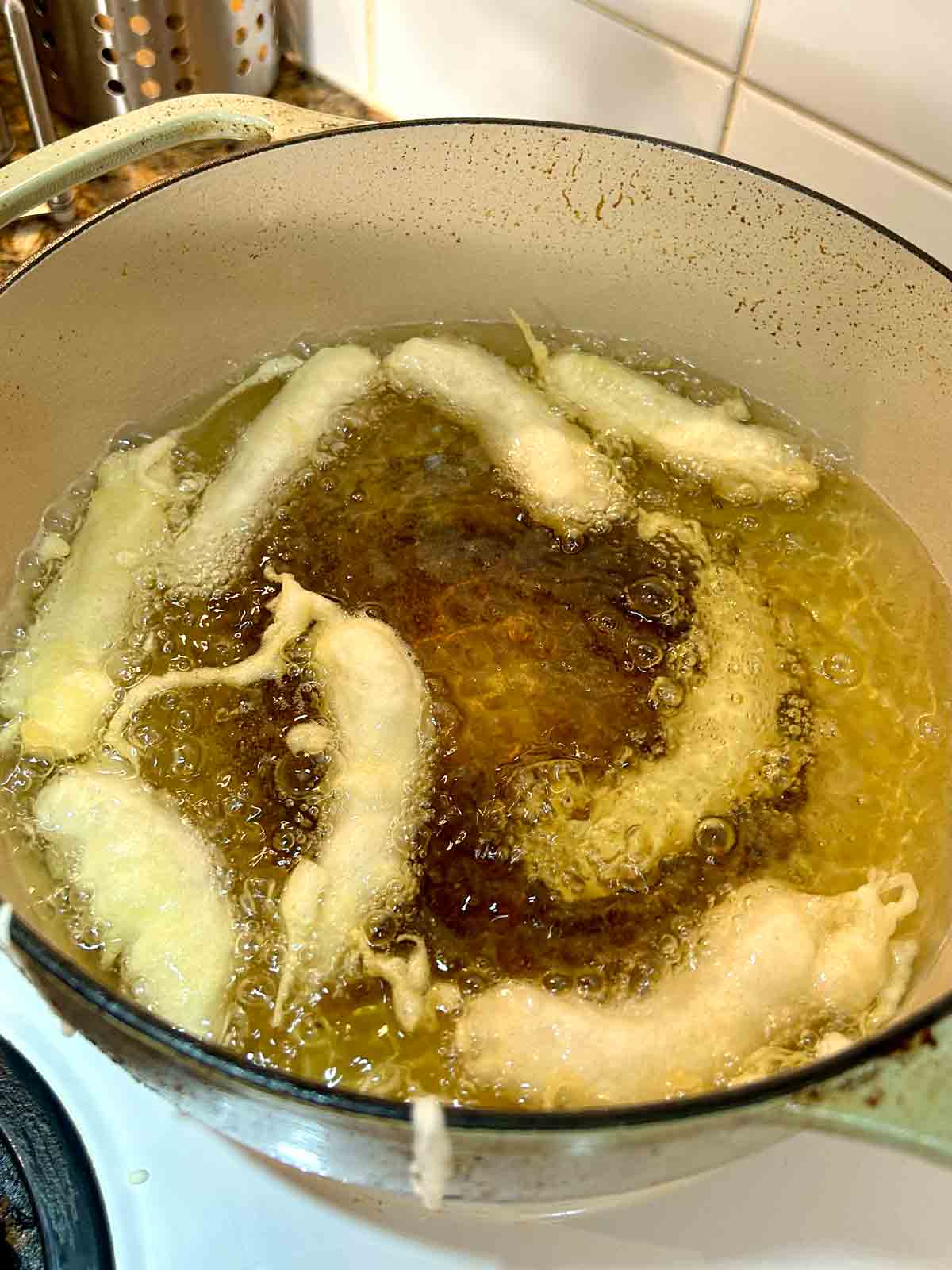 chicken fingers after being dropped into hot oil; their color is still pale white.