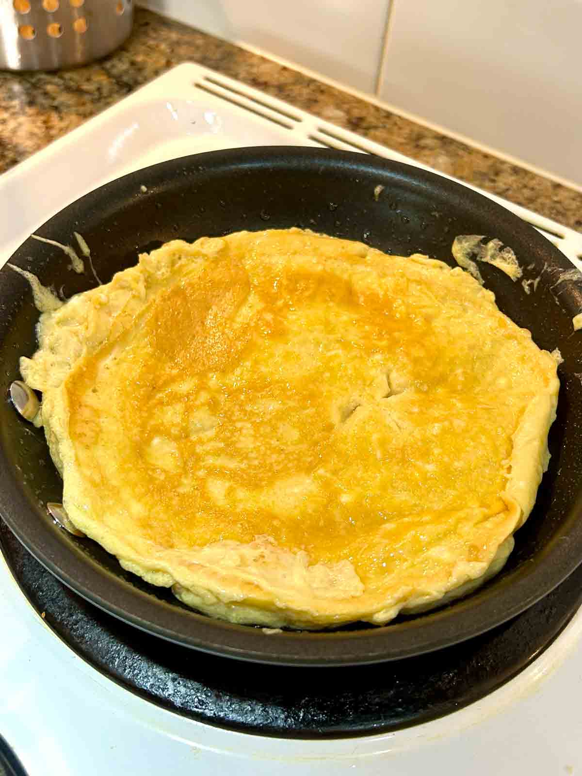 egg omelet cooking in pan.