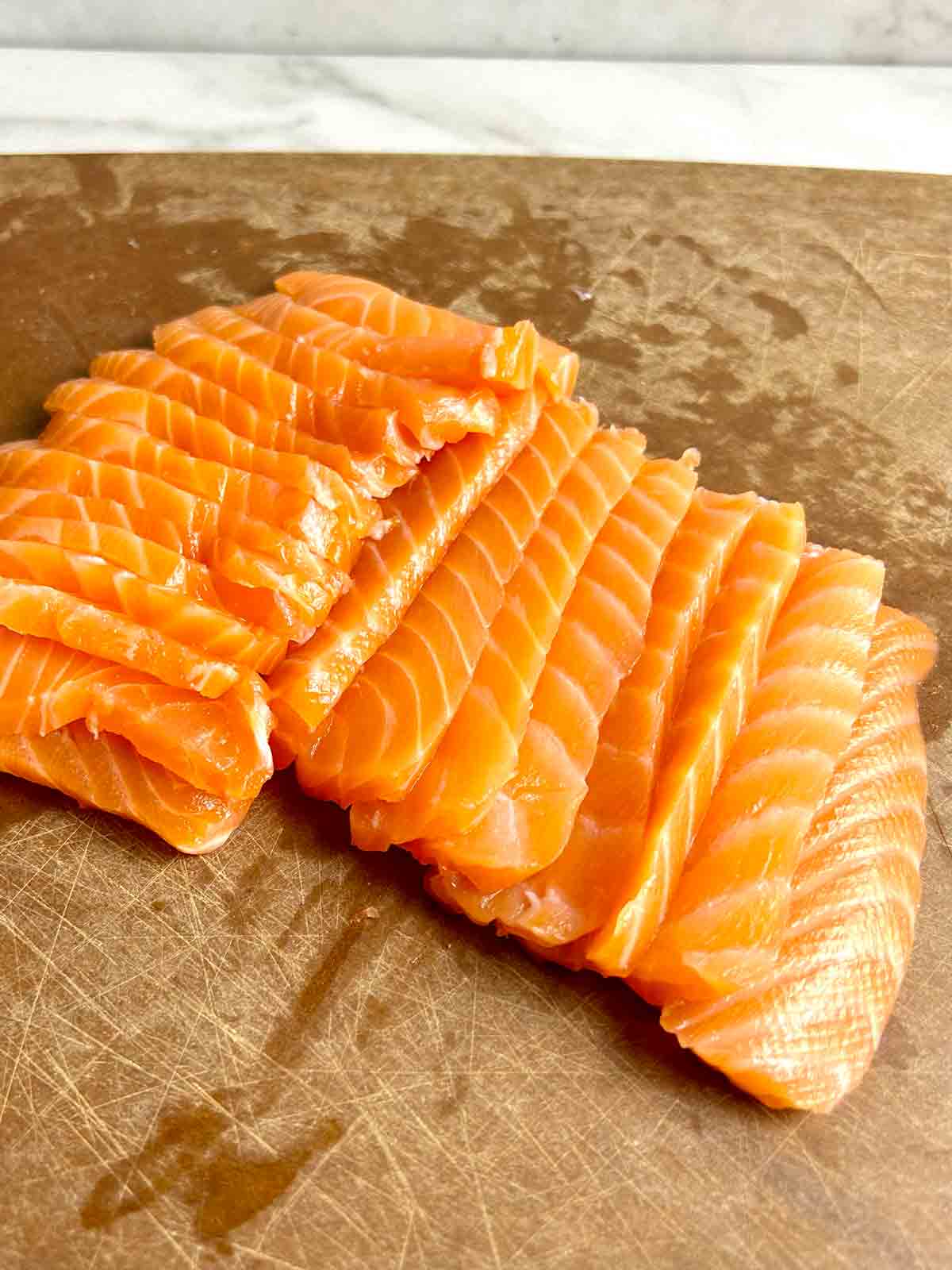 slices of salmon sashimi on cutting board.