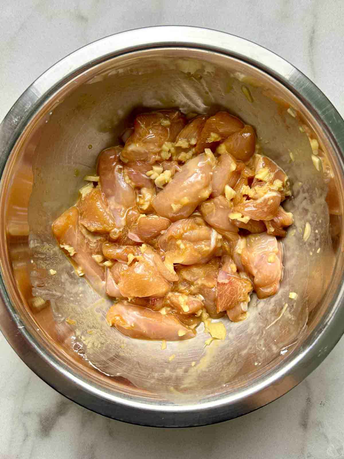 pieces of chicken being marinated in bowl.