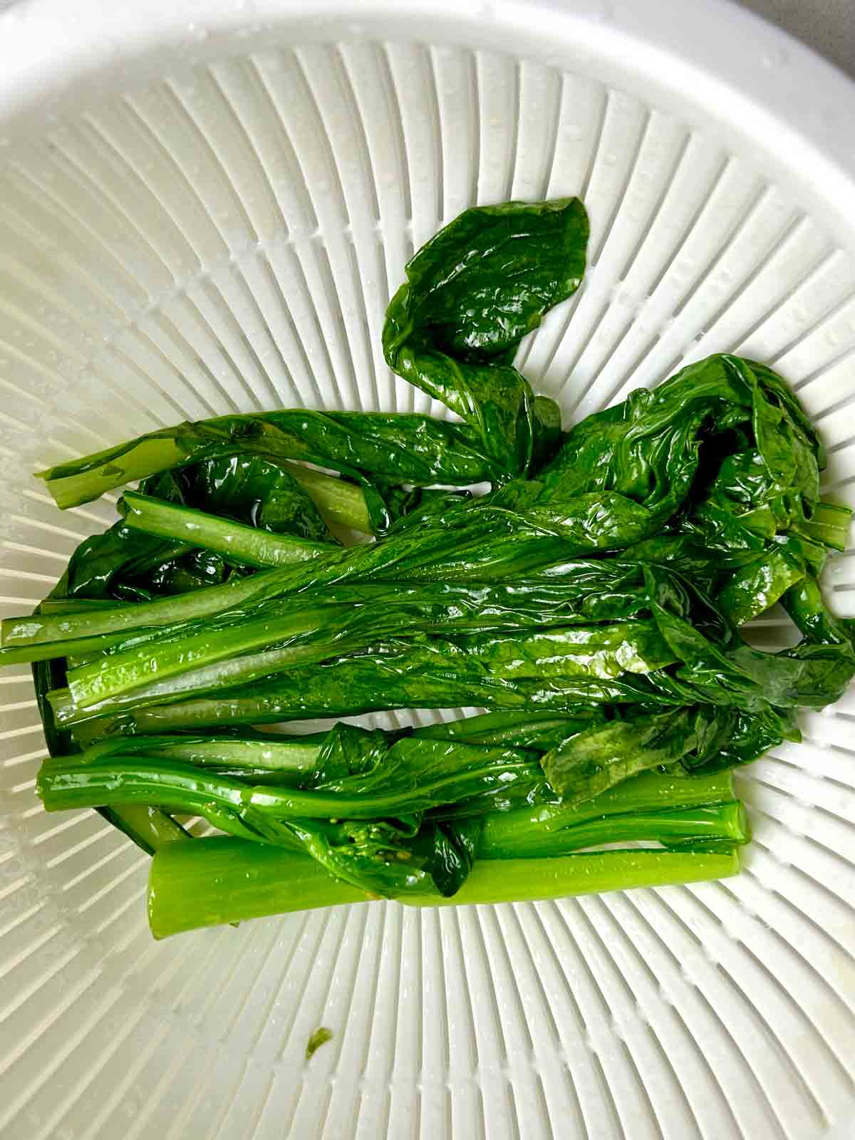 cooked yu choy in colander.