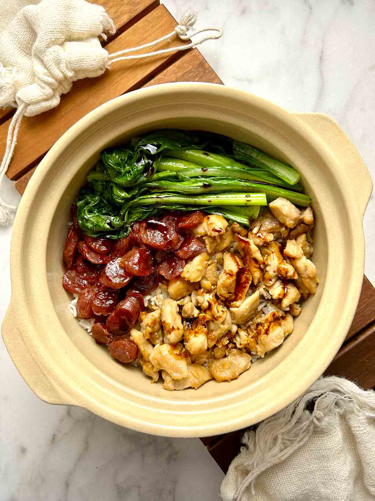 overhead shot of clay pot rice with chicken, Chinese sausages, and yu choy.