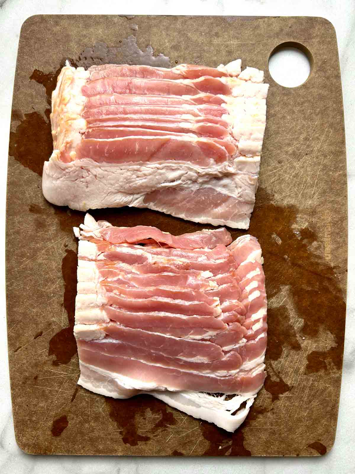 bacon strips cut in half on cutting board.