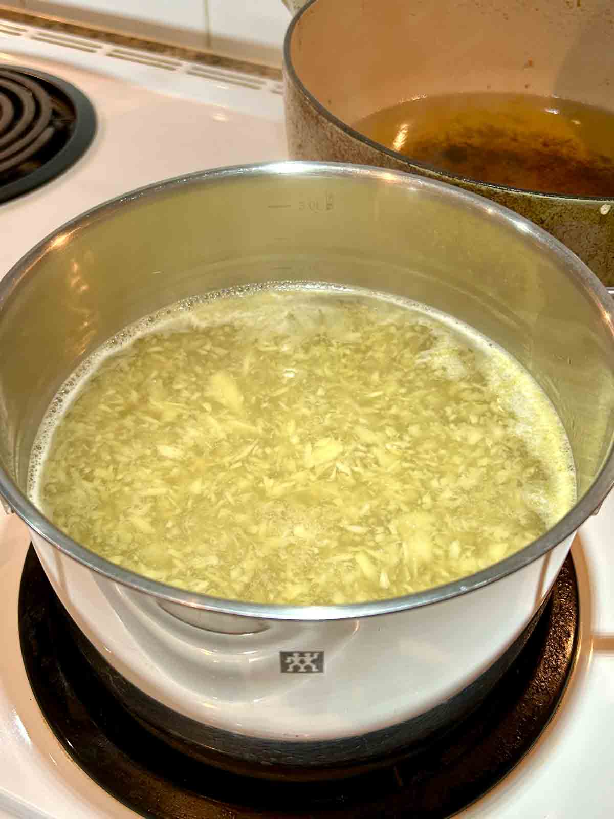 chopped ginger being boiled in pot of water.