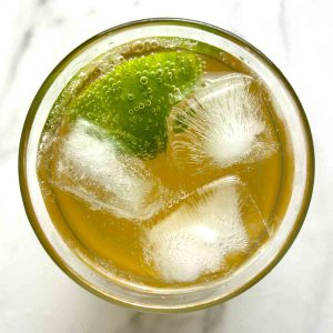 overhead shot of ginger ale in cup with ice and wedge of lime.