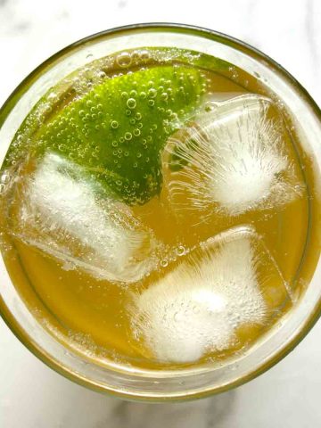 overhead shot of ginger ale in cup with ice and wedge of lime.