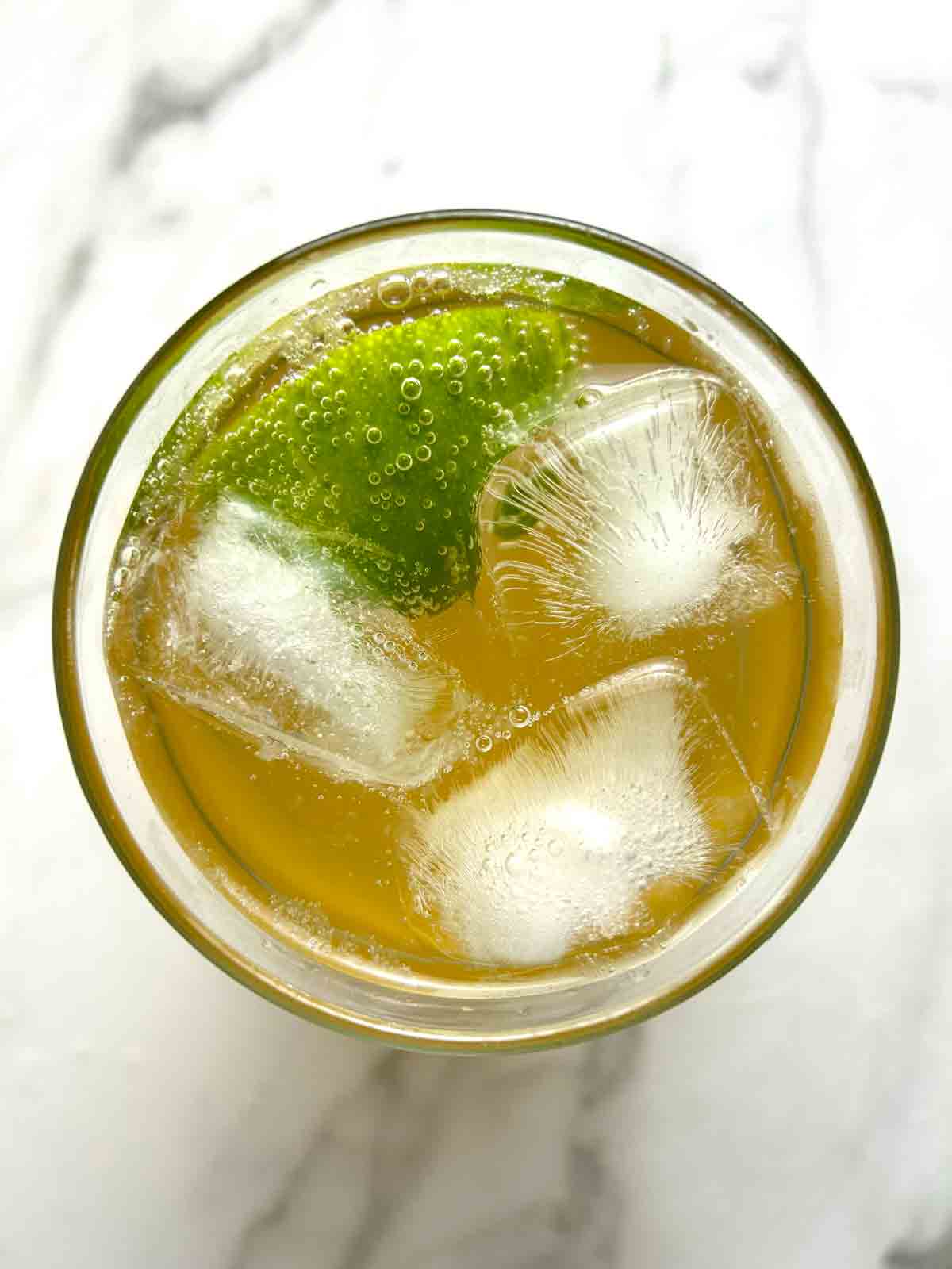 overhead shot of ginger ale in cup with ice and wedge of lime.