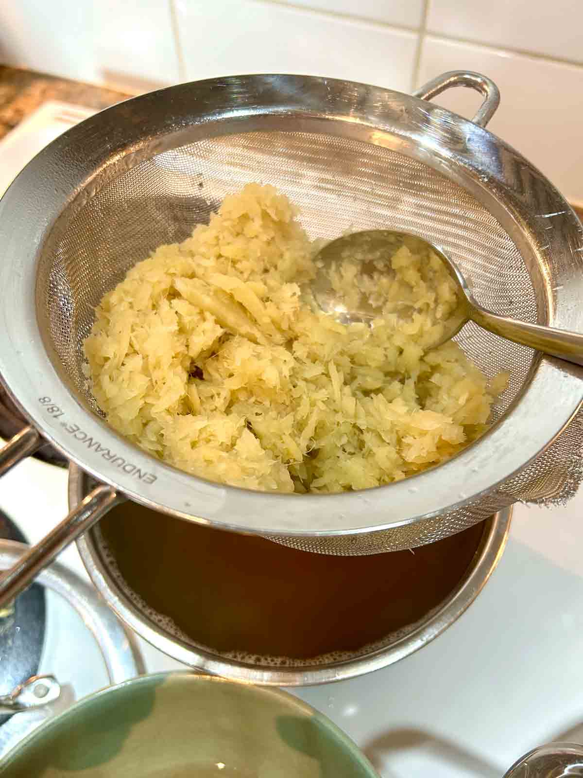 ginger being strained through fine-meshed sieve.