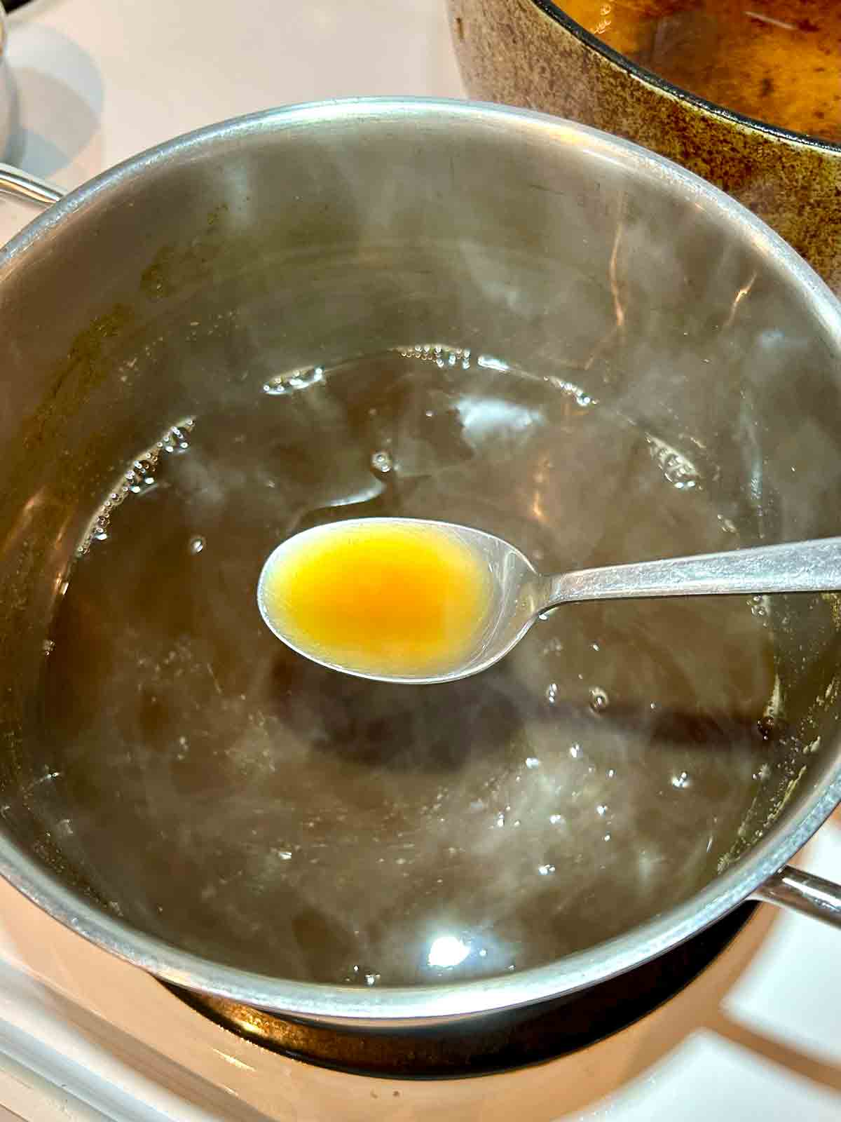 spoon lifting ginger syrup from pot.