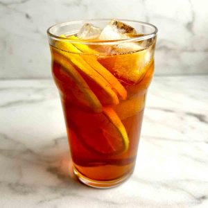 tall glass of lemon tea with lemon slices and ice cubes.