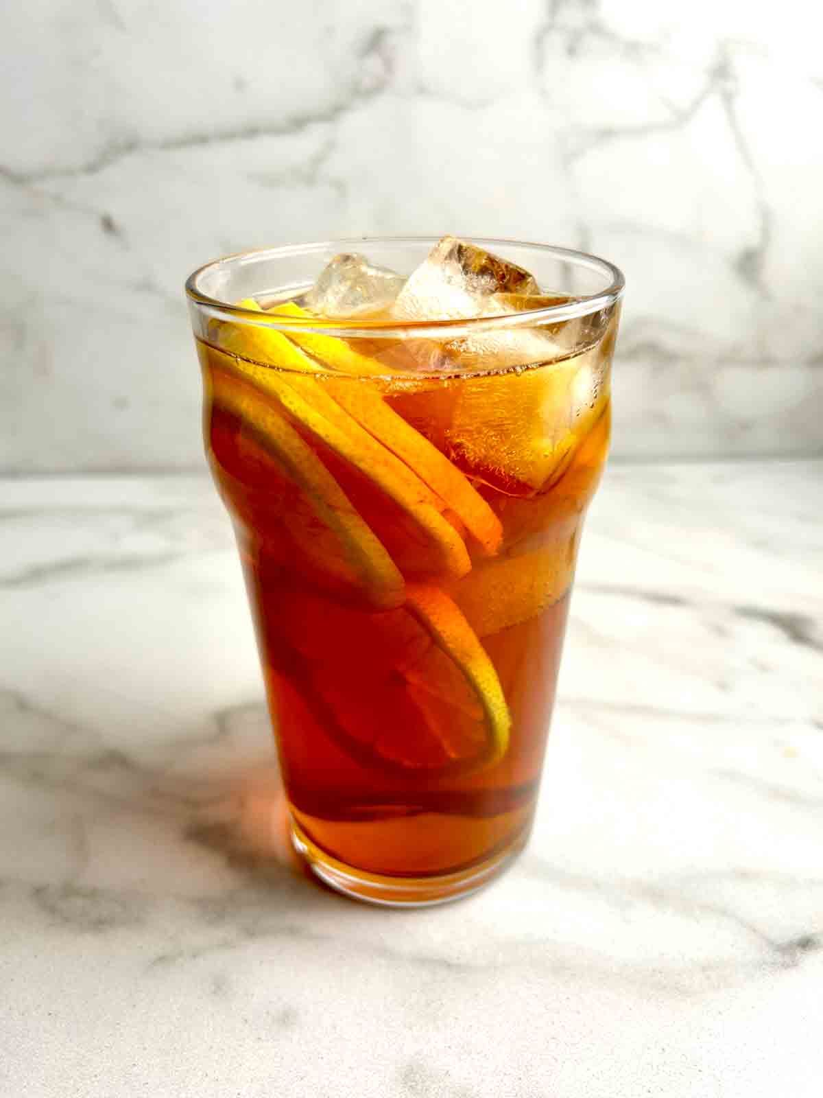 tall glass of lemon tea with lemon slices and ice cubes.