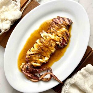 plate of grilled squid with soy butter sauce drizzled all over.