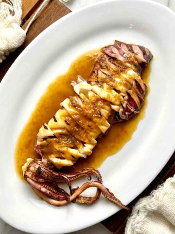 plate of grilled squid with soy butter sauce drizzled all over.