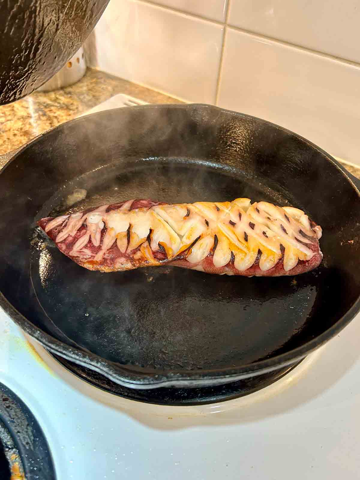 squid head being grilled in cast-iron pan.