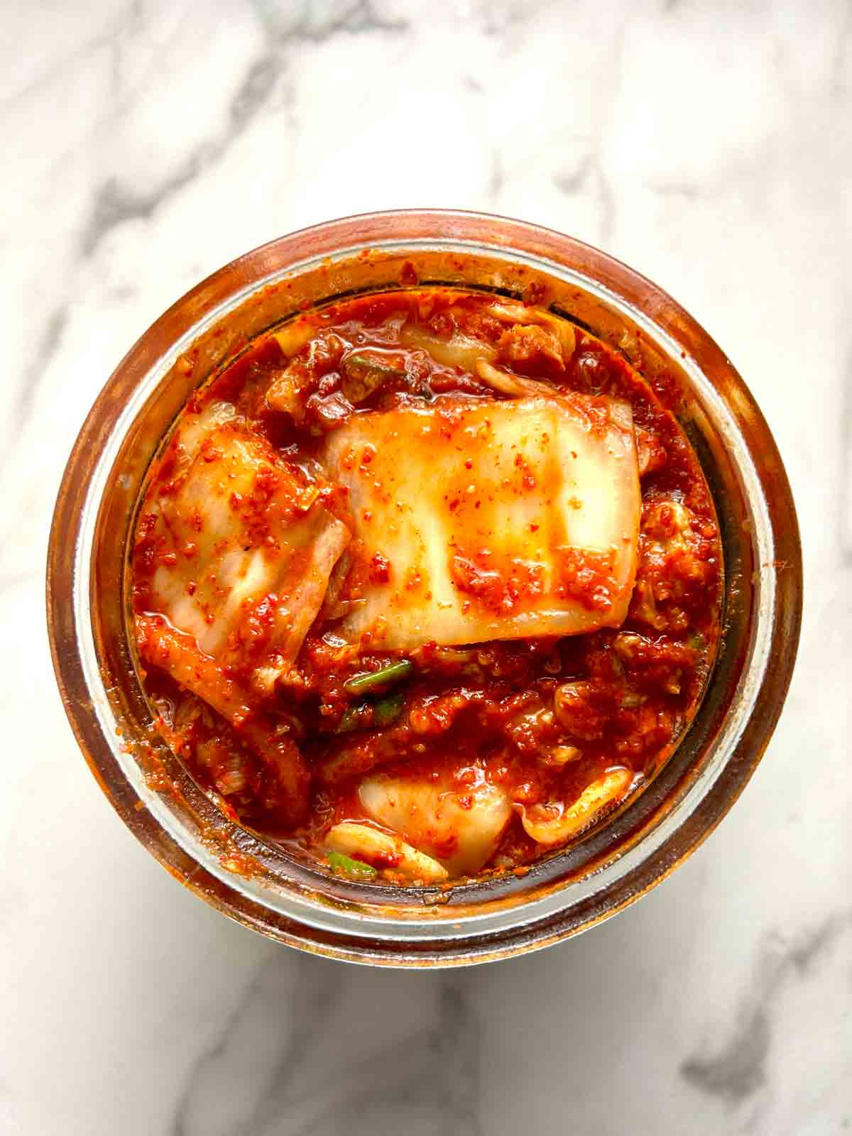 overhead shot of kimchi in glass jar.