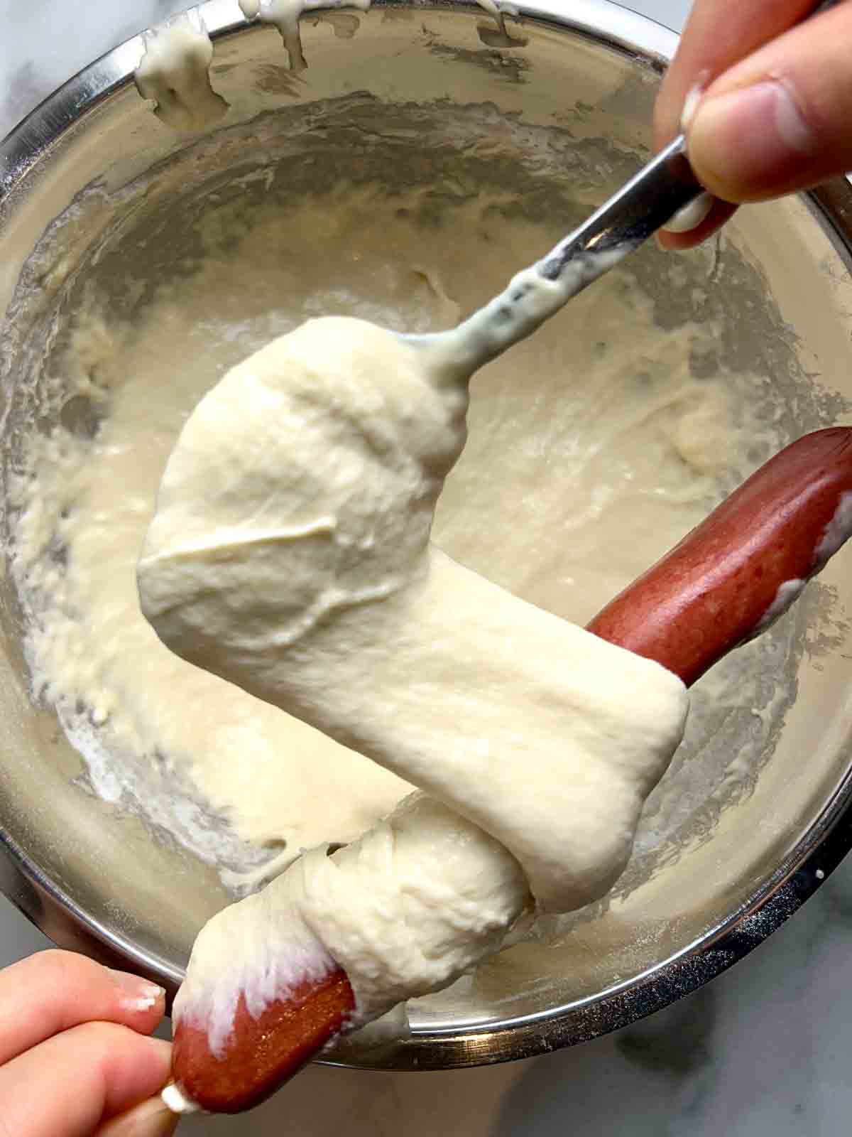 hot dog being wrapped with batter.