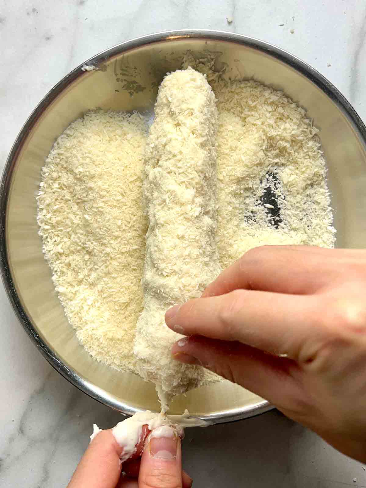 corn dog being coated with panko.