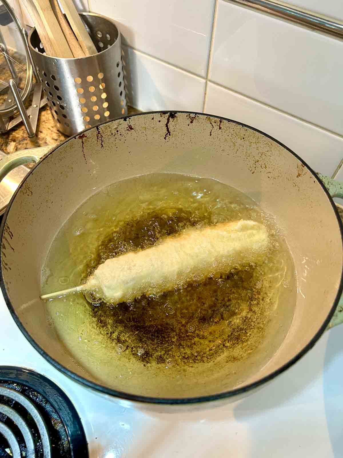 corn dog being fried in hot oil.