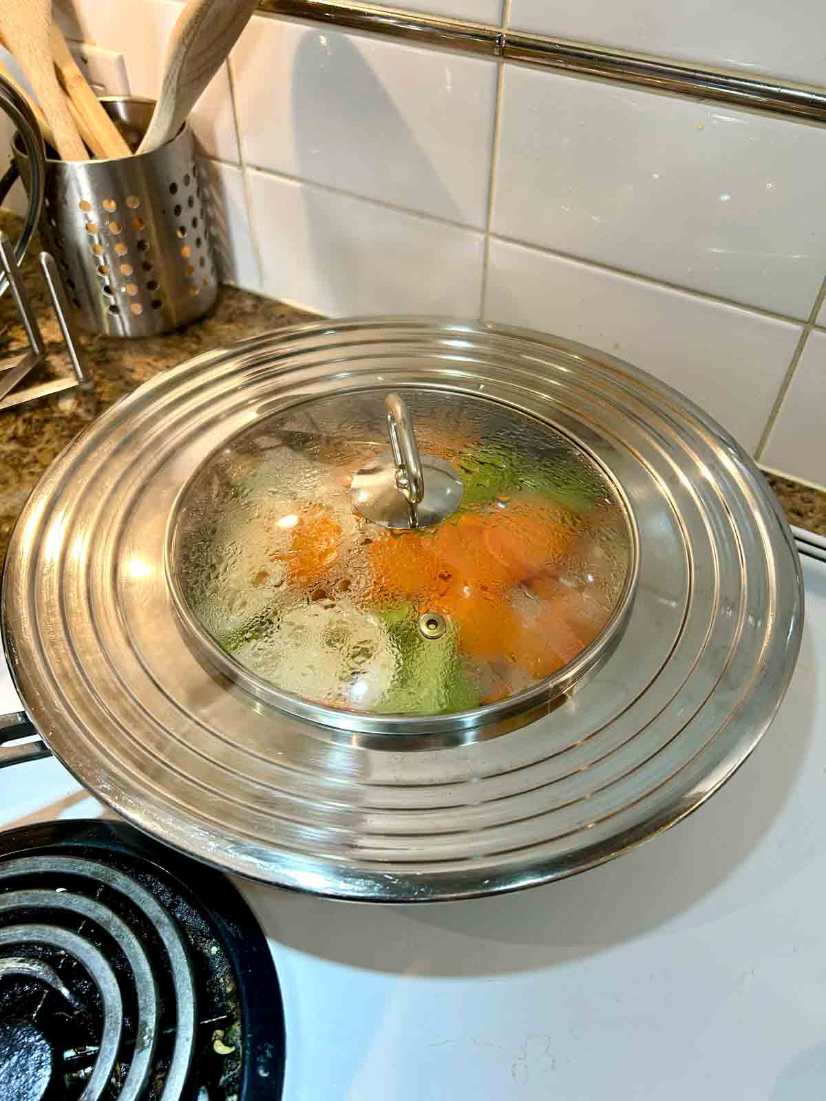 veggies steaming in pan with lid over top of the pan.