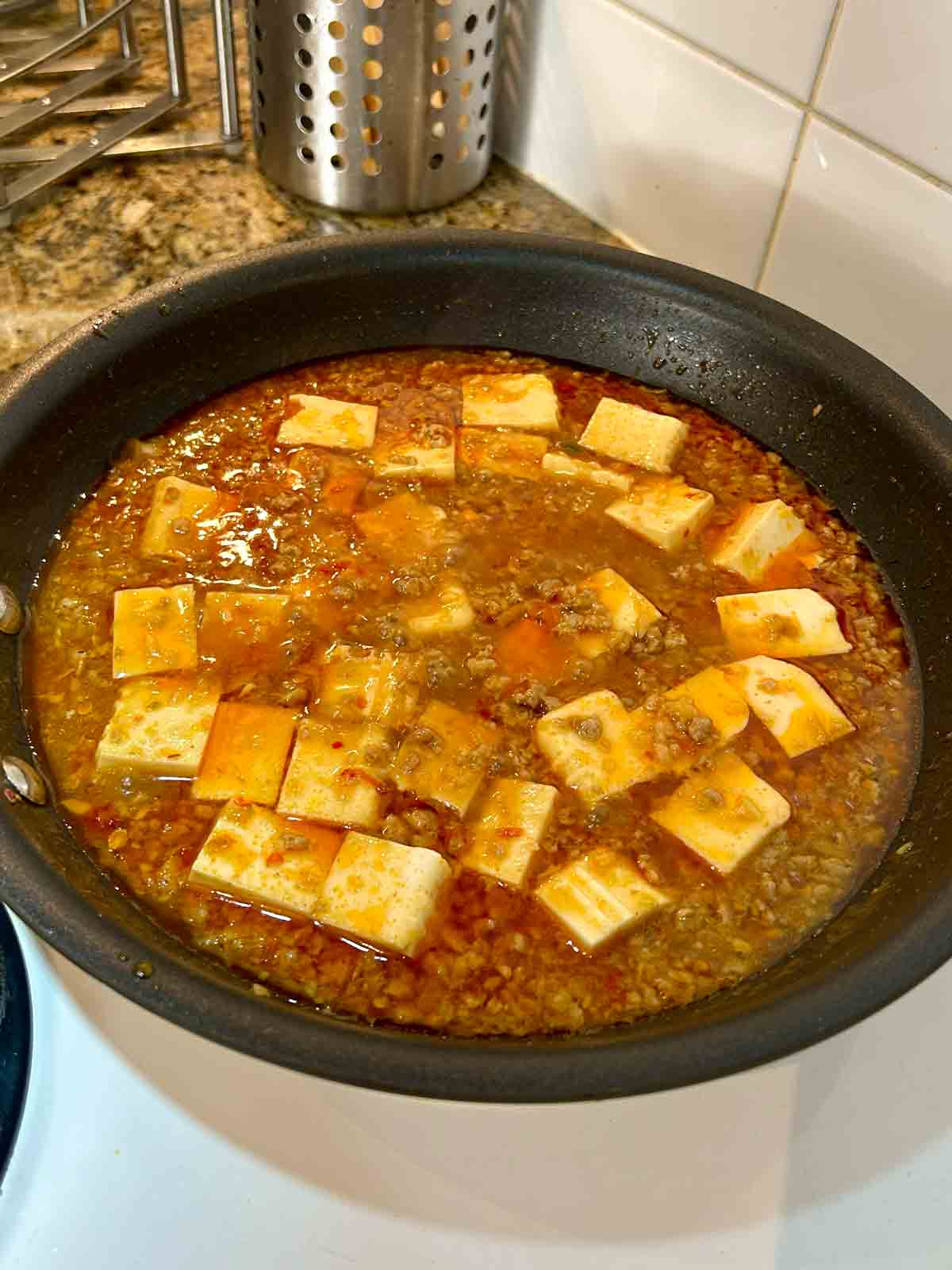 tofu simmering in sauce.