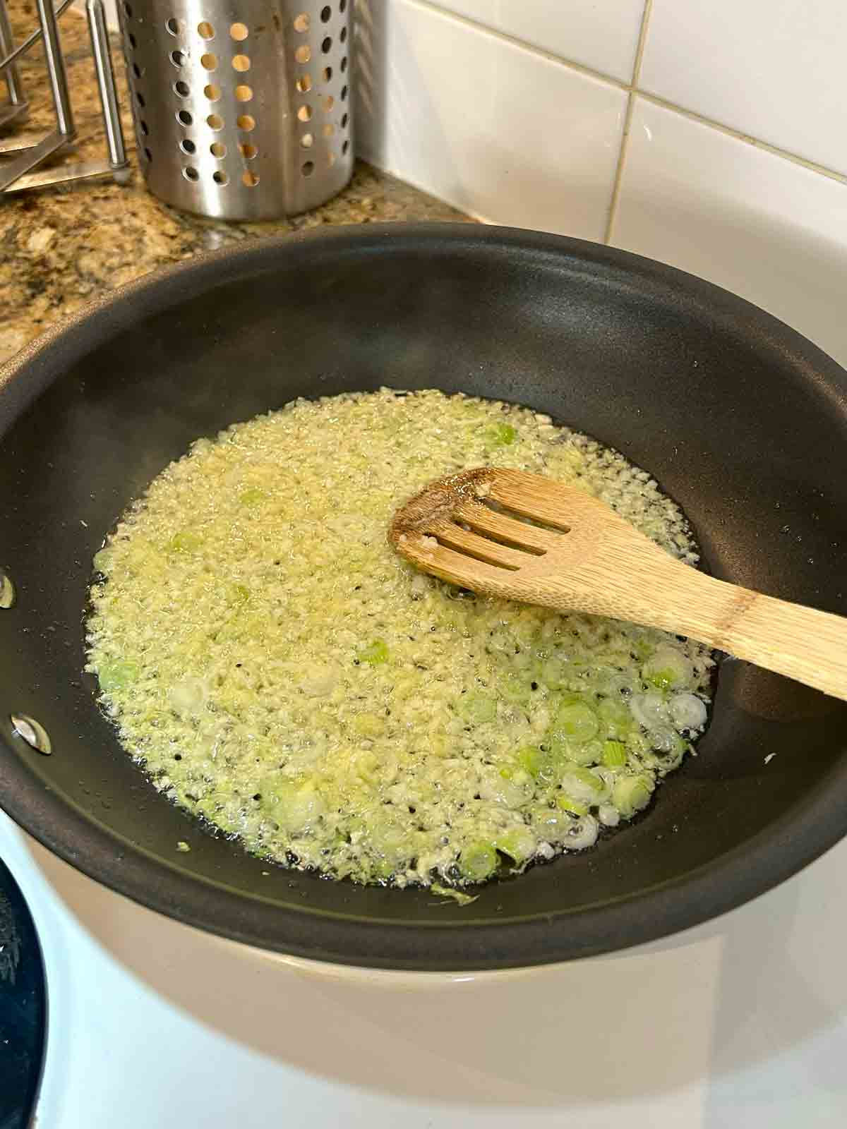 aromatics being stir-fried in pan.