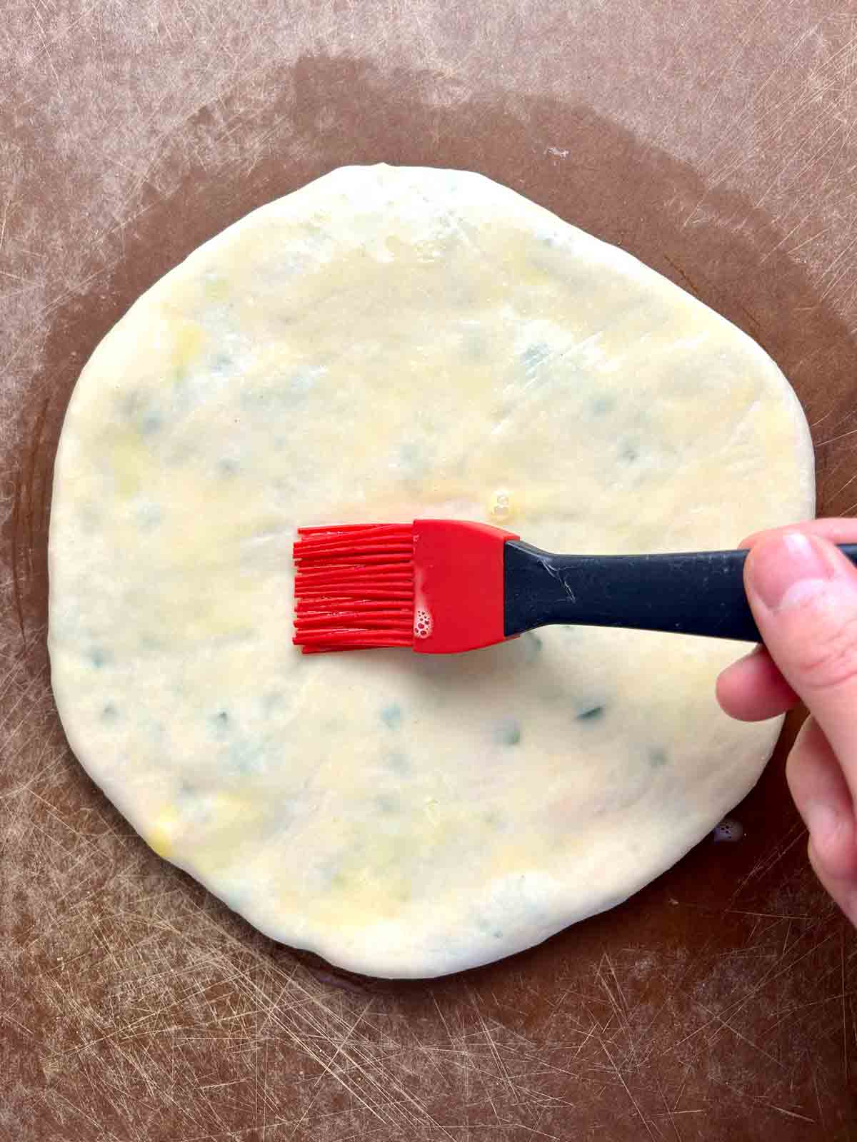 egg wash being brushed onto dough.