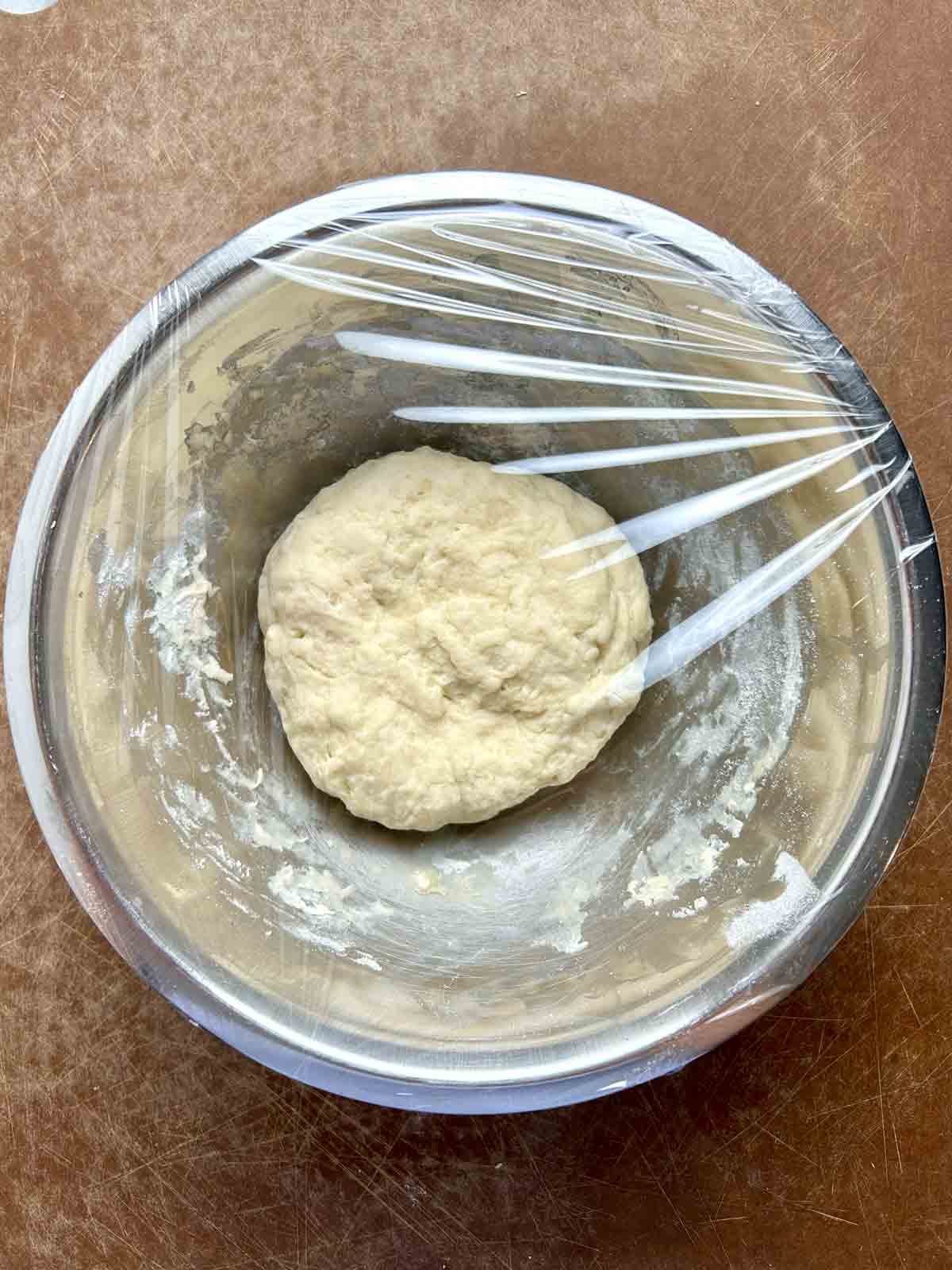 dough in bowl, covered with plastic wrap.