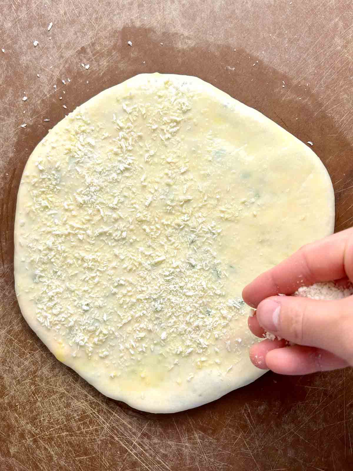 breadcrumbs being sprinkled on dough.