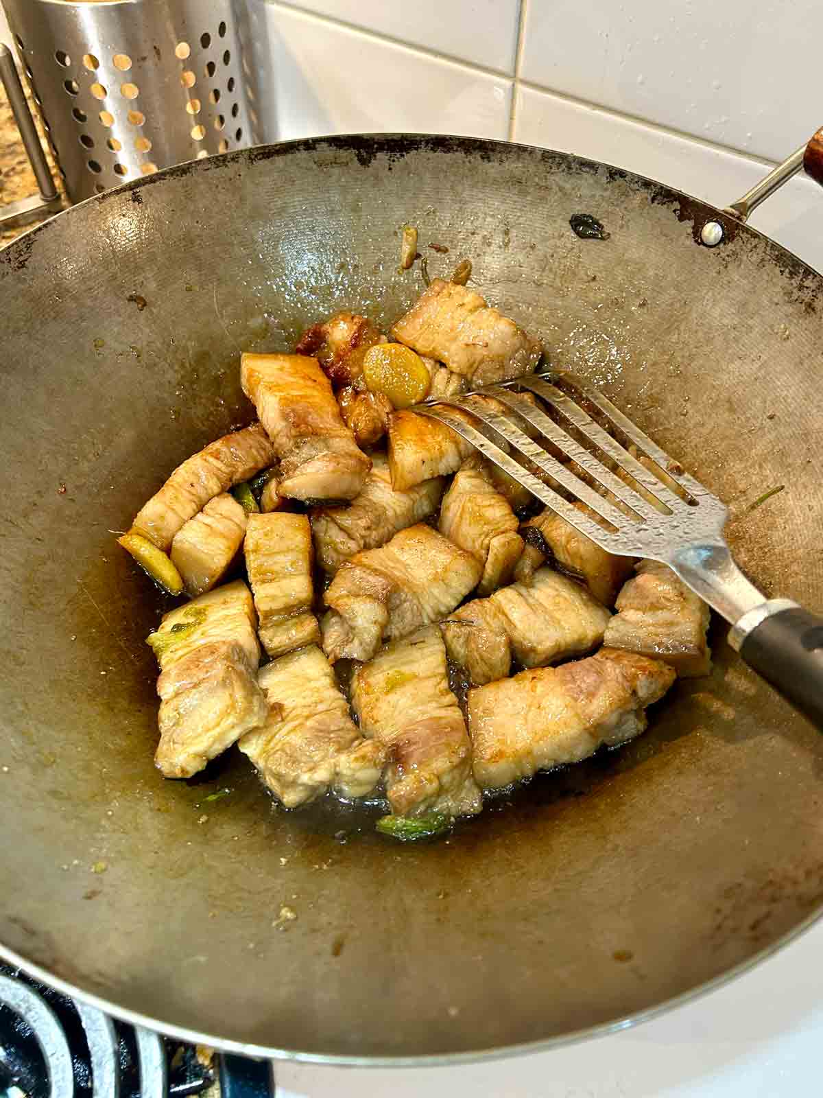 pork belly pieces being caramelized with sugar in wok.