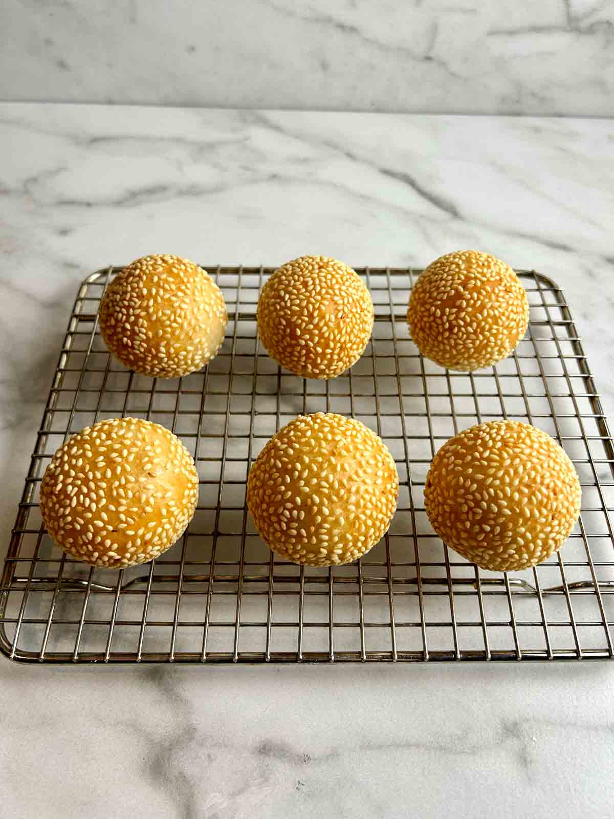 fried sesame balls drying on wire rack.