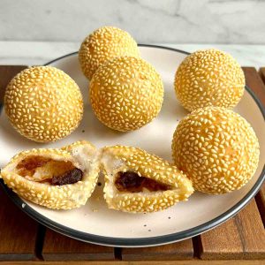 plate of fried sesame balls with one cut in half to show the filling inside.