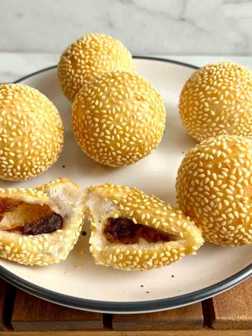 plate of fried sesame balls with one cut in half to show the filling inside.