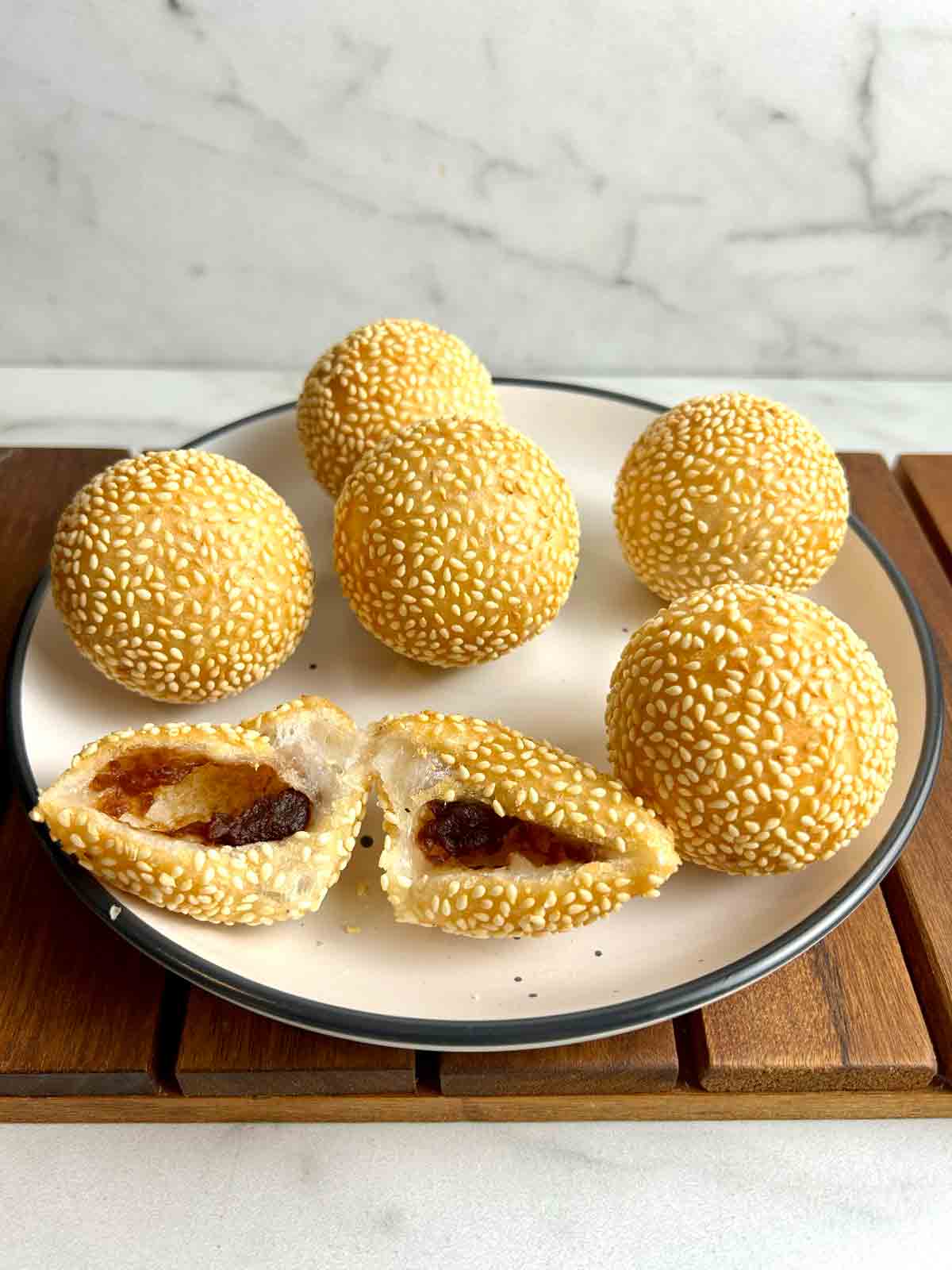 plate of fried sesame balls with one cut in half to show the filling inside.