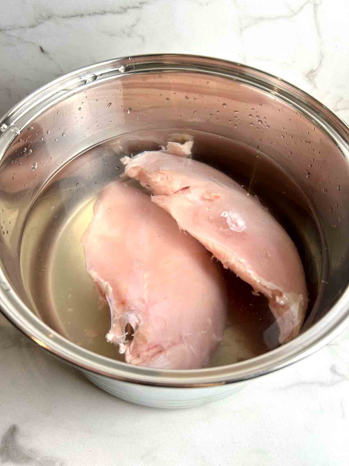 turkey breasts brining in pot of salted water.