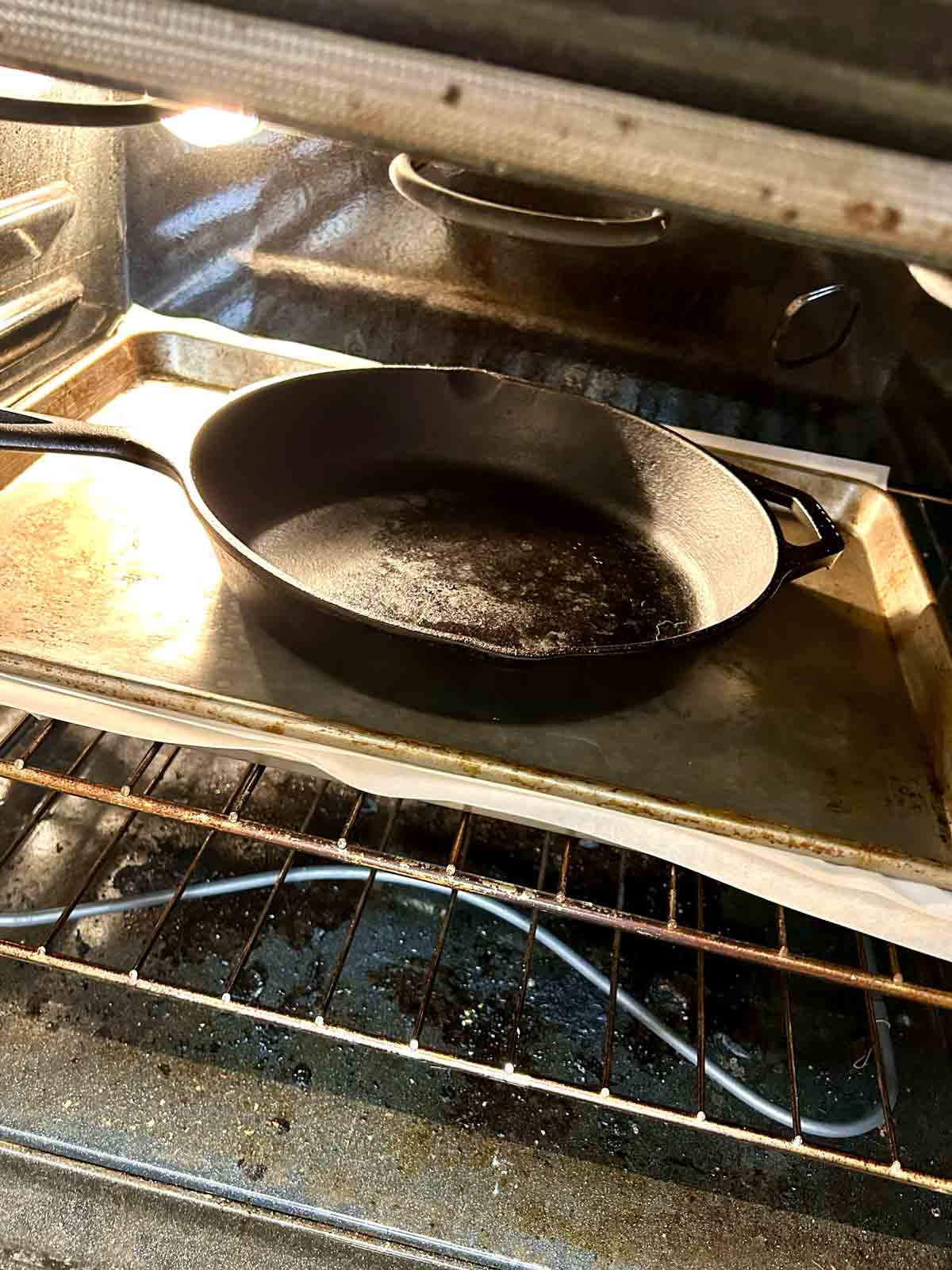 cart iron pan placed on top of baking sheet that is cooking crispy turkey skin.