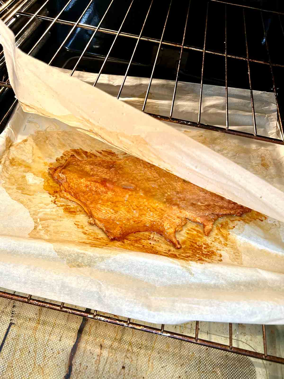 parchment paper being lifted off crispy turkey skin.